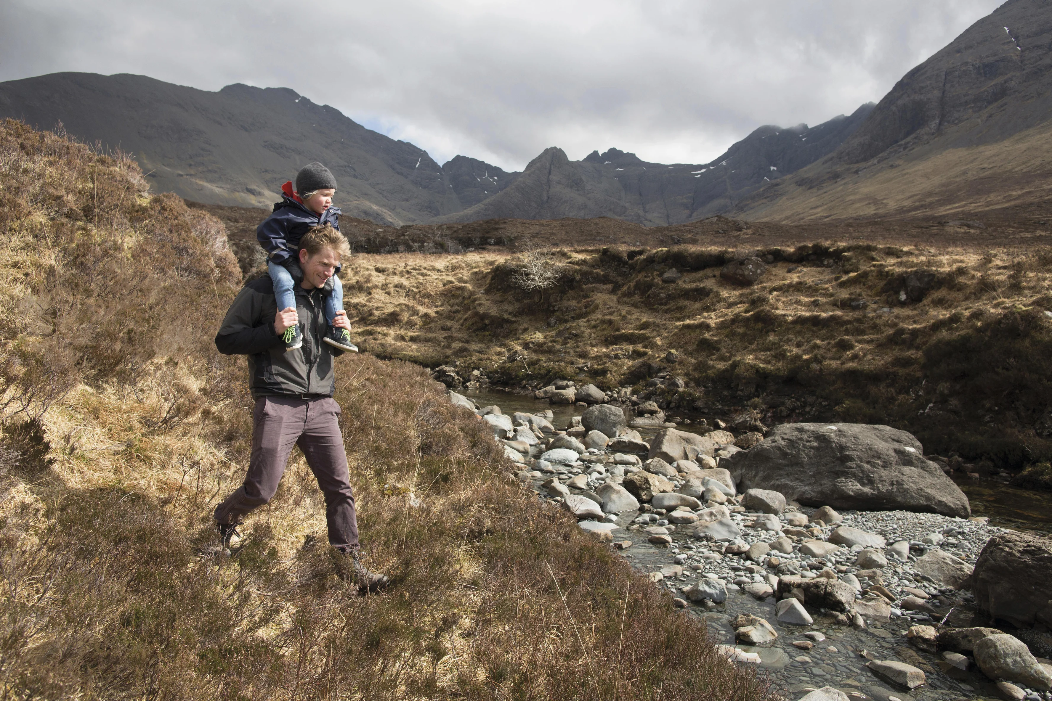 a man and a boy walking on a rocky path in a valley