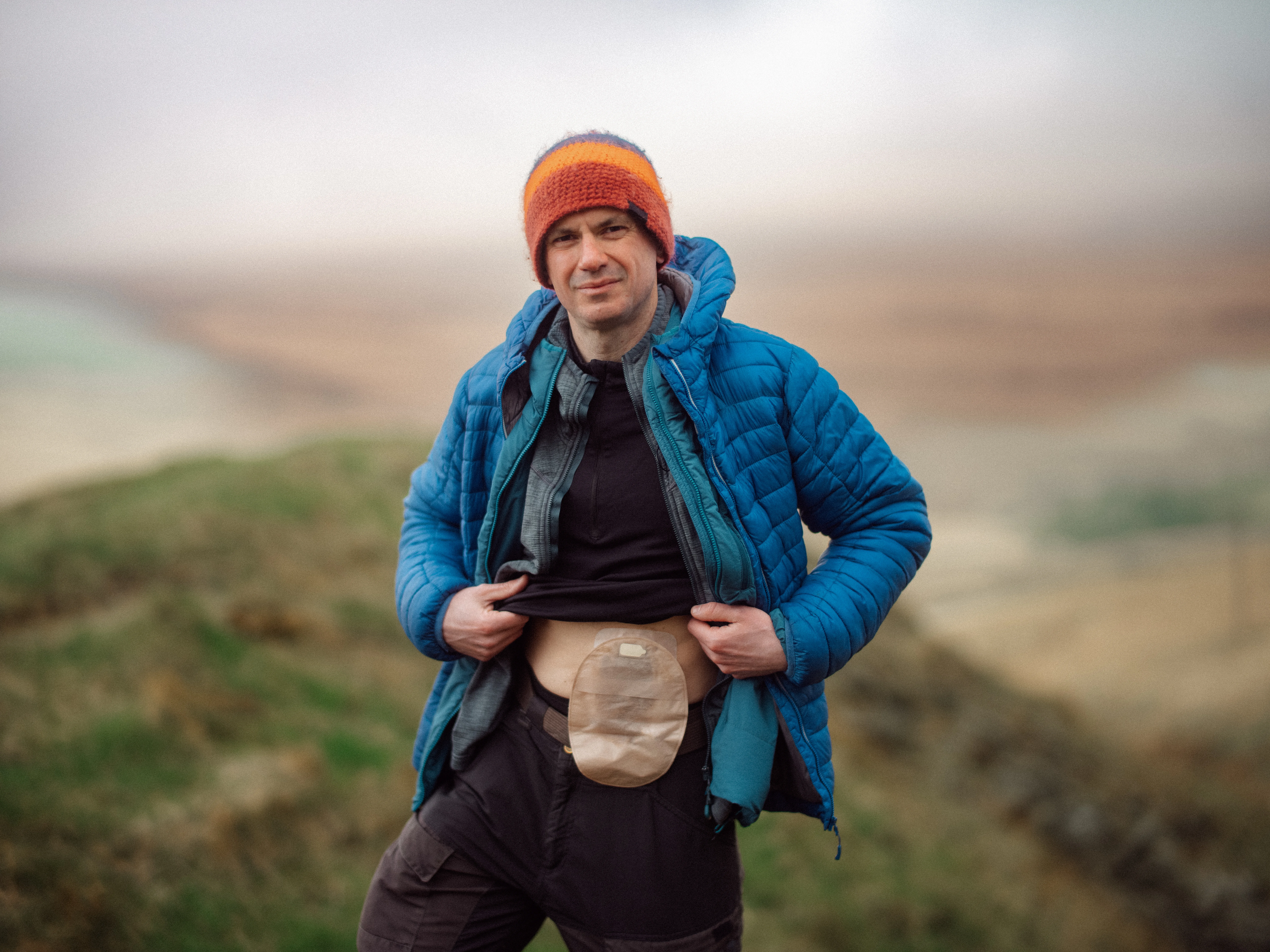 a person wearing a hat and a backpack standing on a hill